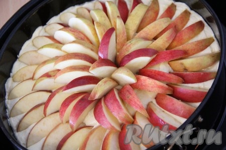 Выложить кусочки яблок на тесто и слегка их утопить в тесто.