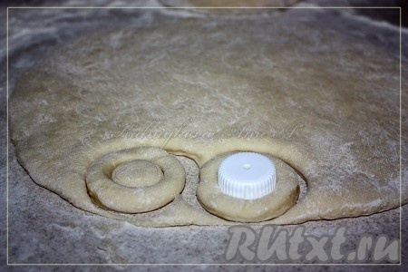 Раскатать тесто в пласт толщиной около 1 см. Вырезать пончики при помощи кружки, а середину пончика вырезать при помощи подходящего размера крышки.
