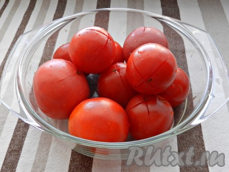 На помидорах сделать крестообразные надрезы, сложить в миску и залить кипятком на 2-3 минуты.
