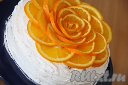 Апельсины хорошо вымыть и тонко нарезать кружочками. Выложить кружочки апельсина на верхушку торта в виде цветка.