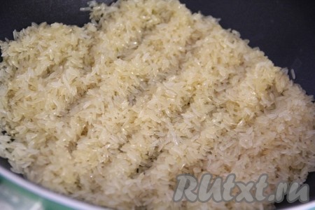 Рис выложить в сито, тщательно промыть под проточной водой, затем оставить на несколько минут в сите, чтобы стекла лишняя вода. В глубокую сковороду влить растительное масло, прогреть его, всыпать рис. Обжарить рис, периодически помешивая, на среднем огне в течение нескольких минут. Масло должно полностью впитаться в рис.