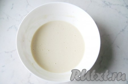 Прежде всего сделаем опару для оладий. Для этого молоко нужно подогреть до 38-40 градусов, перелить в глубокую тарелку, добавить сухие дрожжи и 1 столовую ложку сахара, перемешать.