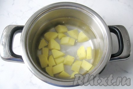 В кастрюлю налить 1,7-2 литра воды. Очищенный картофель нарезать кубиками, добавить в кастрюлю с водой. Кастрюлю накрыть крышкой, поставить на огонь, после закипания воды уменьшить огонь.