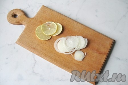 Репчатый лук почистить и помыть. Лимон вымыть. Лук нарезать на кольца, а лимон - на достаточно тонкие кружочки.