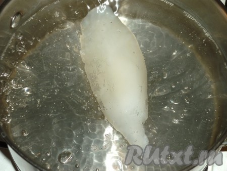 Если тушки кальмара заморожены, тогда их нужно полностью разморозить при комнатной температуре. Если кальмары не очищены, тогда с них нужно удалить плёнку, убрать хорду, находящуюся внутри тушки. Промыть кальмаров под проточной водой. В кастрюлю налить воду и довести до кипения, добавить 0,5-1 чайную ложку соли. Опускать тушки кальмара (лучше по одному) в кипящую воду на 2 минуты, но не больше, иначе кальмар станет резиновым. 