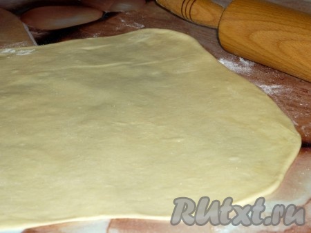 Разделить тесто на две части. Каждую часть раскатать на хорошо посыпанной мукой поверхности в тонкий пласт, размером примерно 30 на 40 сантиметров. 
