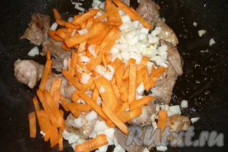 Лук и морковь почистить, помыть. Лук нарезать кубиками, морковь - соломкой, добавить овощи к обжаренной свинине, перемешать и жарить 4-5 минут, периодически перемешивая. 
