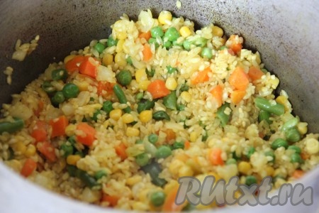 В кастрюлю с рисом добавить слегка обжаренные овощи, перемешать.