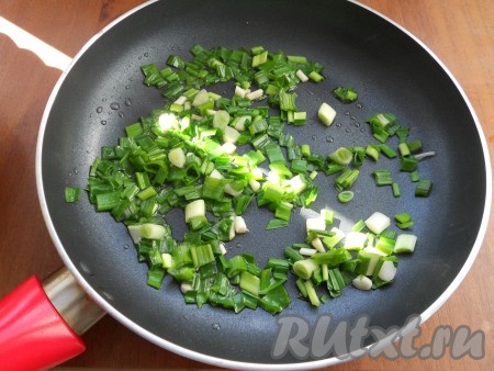 Для приготовления начинки в сковороде разогреть растительное масло, добавить измельченный зеленый лук и зелень чеснока. Постоянно помешивая, обжарить зелень на небольшом огне в течение 2-3 минут.
