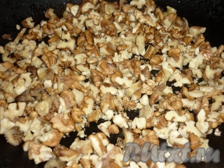Грецкие орехи немного измельчить ножом. Орехи обжарить на сухой сковороде, помешивая, в течение 2-3 минут.