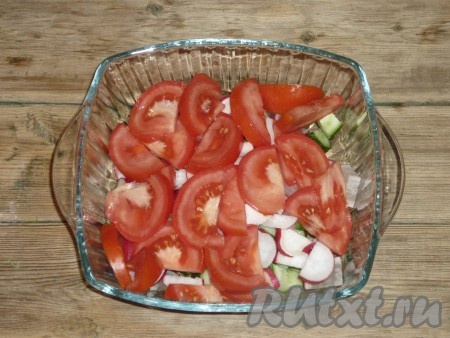 Помидор нарезать дольками и добавить в салат к редиске и огурцам. 