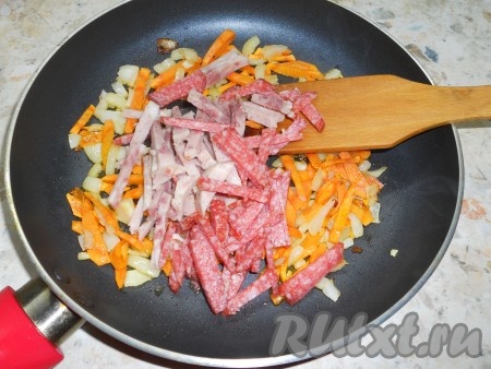 Обжарить овощи на среднем огне 4-5 минут, при периодическом помешивании. Добавить в сковороду нарезанную соломкой или кубиками колбасу. Обжаривать все еще 3-4 минуты.
