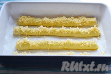 Смазанные яйцом булочки из дрожжевого теста сверху обильно посыпаем натёртым сыром и отправляем форму в разогретую духовку. Выпекаем 20-30 минут при температуре 180 градусов. Сыр полностью должен растаять и припечься. Булочки приобретут золотистый цвет.
