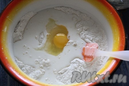 Далее добавить в смесь муки и сахара молоко и яйцо. Перемешать силиконовой лопаткой.
