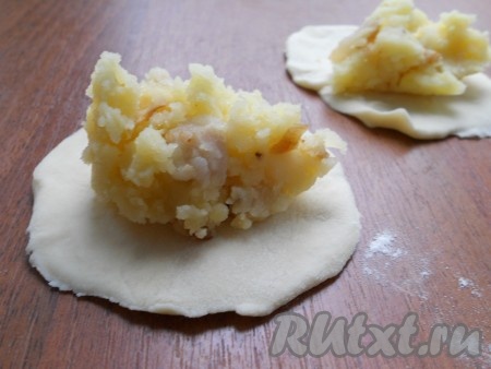 Далее тесто для вареников обмять, разделить его на небольшие кусочки, раскатать в лепешки. На каждую лепешку поместить по 1 столовой ложке начинки из картофеля и сала.
