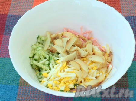 Далее нарезать картофель. Добавить его в миску к огурцам, колбасе и яйцам, перемешать салат, посолить и поперчить.
