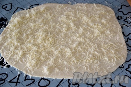 Сыр натереть на мелкой тёрке. Посыпать пласт теста сыром.