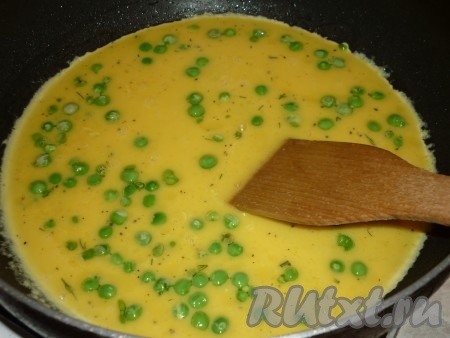Вылить яично-молочную массу в сковороду с зелёным горошком. Накрыть крышкой и готовить омлет на среднем огне около 5 минут.
