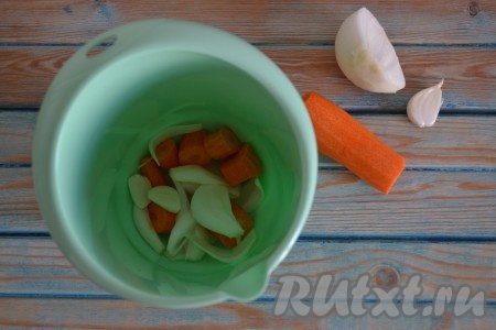 Очищаем и крупно нарезаем половинку моркови, одну луковицу, два зубчика чеснока и выкладываем в чашу блендера.

