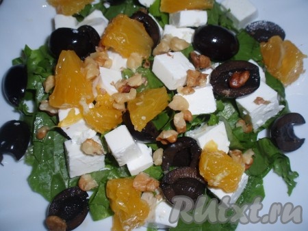 Дольки апельсина очистить от пленок, нарезать на 2-3 части и выложить на салат. Орехи раздробить и посыпать ими салатик.
