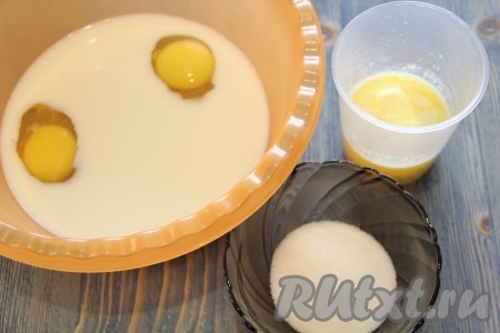 В глубокую миску влить молоко, добавить яйца. Сливочное масло растопить и слегка остудить.