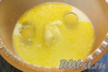 В миску с молоком и яйцами влить растопленное масло, всыпать сахар, тщательно перемешать венчиком.