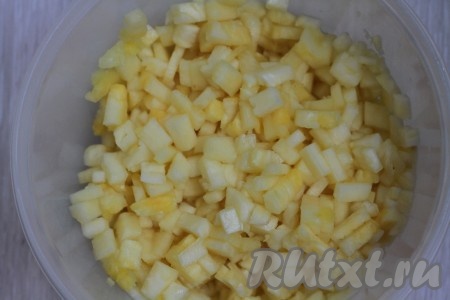 Прежде всего ананас нужно очистить. Ножом срезаем нижнюю и верхнюю части ананаса, затем снимаем кожицу, нарезаем на круглые дольки и из каждой дольки ананаса удаляем жесткую середину. Очищенный ананас нарезаем кусочками и складываем в емкость.
