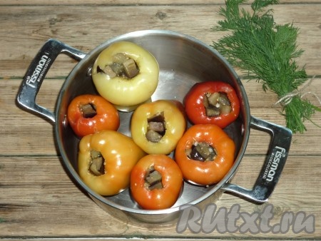 Подготовленные болгарские перцы наполнить жареными баклажанами и сложить их в кастрюлю. 
