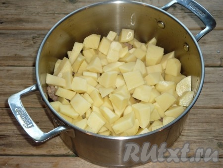 Картофель очистить, вымыть, нарезать крупными кубиками и отправить в кастрюлю к свинине. 
