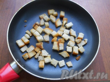 Кубики хлеба поместить в сковороду, влить 1-2 чайных ложки растительного масла и обжарить, перемешивая, на небольшом огне до румяного цвета. Сухарики переложить со сковороды на тарелку.
