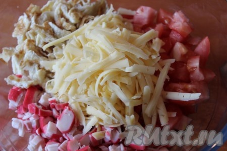 В глубокой миске соединить помидоры, крабовые палочки, сыр, нарезанные яичные блинчики, добавить пропущенный через пресс чеснок, немного посолить салат.
