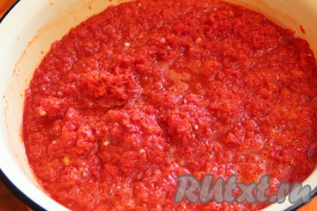Первым делом приготовим густое томатное пюре, для этого рецепта понадобится 2 килограмма пюре, поэтому 4 килограмма помидоров перекручиваем на мясорубке, выливаем в кастрюлю и отправляем на огонь. Варим на небольшом огне, примерно 30-40 минут, пока помидоры не уварятся и масса не станет густой. Томатное пюре готово. Отставляем его в сторону. Отдельно пропускаем дольки чеснока через пресс и заливаем подсолнечным маслом, оставляем на 5-10 минут, чтобы масло напиталось ароматом. Чеснок с маслом наливаем в кастрюлю, в которой будем варить аджику, и прогреваем на небольшом огне около 5 минут. Сладкий и острый перцы перекручиваем на мясорубке и выливаем в кастрюлю с чесноком. Варим на медленном огне около 1 часа, периодически помешивая.

