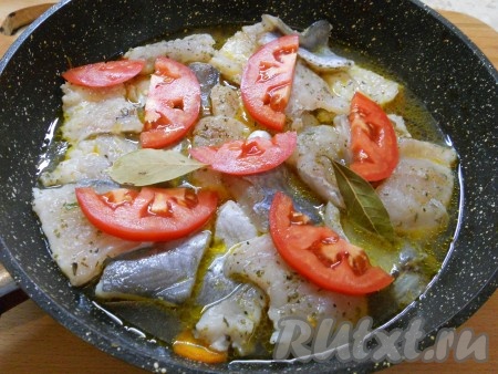 На рыбу разместить кружочки или полукружочки свежих помидоров, влить бульон, добавить лавровый лист.