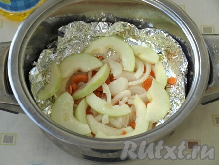 В чашу пароварки выложить фольгу в 2 слоя, смазать верхний слой подсолнечным маслом. Затем выложить овощи: морковь, лук и кабачки.
