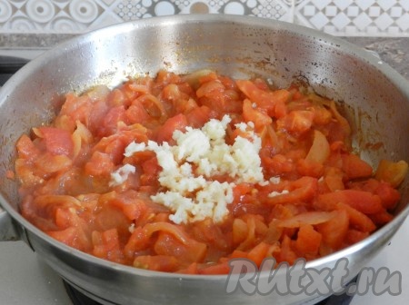 Добавить чеснок, пропущенный через пресс, к помидорам и луку, перемешать и готовить еще 1-2 минуты.
