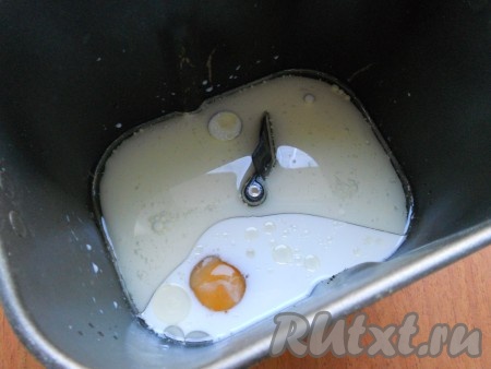 Молоко немного подогреть. Влить тёплое молоко в ведерко хлебопечки. Затем добавить растительное масло и сырое яйцо.