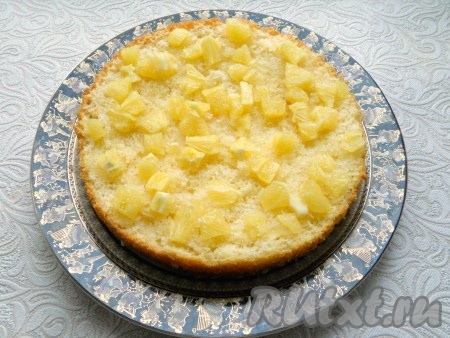 На нижнюю часть бисквита выложить апельсины, а верхнюю - пропитать сиропом.
