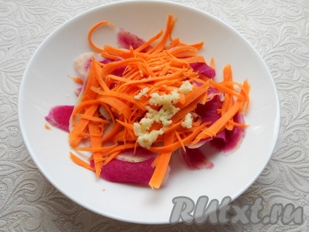 Добавить к редьке морковь, натертую на терке для корейской моркови, и пропущенный через пресс чеснок.
