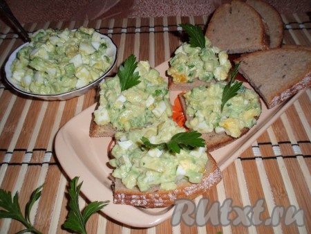 На кусочки хлеба выложить приготовленную начинку, украсить зеленью и подать вкусные, сытные бутерброды с авокадо и яйцом к столу.