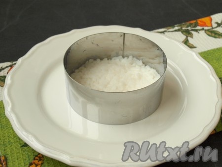 Рис сварить заранее, для этого сухой рис нужно промыть, а затем выложить в кастрюлю с кипящей подсоленной водой, после закипания воды, уменьшив огонь, отварить рис до готовности (в течение 15-20 минут), откинуть на дуршлаг, дать стечь воде, оставить до полного остывания. Для приготовления одной порции салата потребуется 3-4 столовых ложки остывшего риса. Крабовые палочки, если они заморожены, полностью разморозить. Сухарики я приготовила домашние, нарезав белый хлеб на ломтики и подсушив его на сухой сковороде со всех сторон. Для того чтобы приготовить порционно салат "Коррида", нужно на плоскую тарелку поставить кольцо, выложить сначала рис и разровнять.