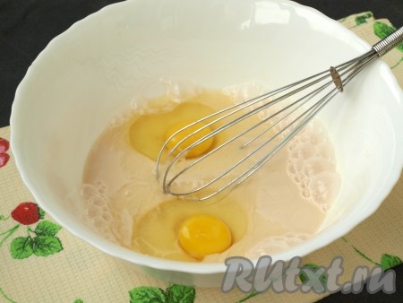 Ряженку нужно немного подогреть, вылив в сотейник, затем перелить в глубокую миску и добавить соль, ванилин и сахар. Вспенить ряженку венчиком и добавить яйца, снова размешать.
