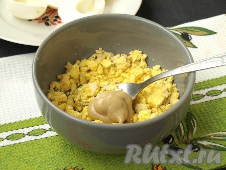 Разрезать пополам яйца, вынуть желтки. Яичные желтки размять вилкой, добавить по вкусу горчицу и выдавить чеснок. Также можно добавить каплю майонеза. Получившуюся смесь хорошо перемешать.