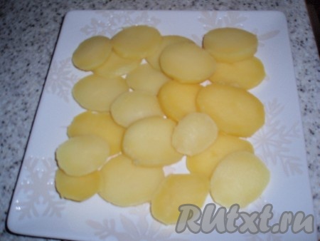Сваренный в мундире и охлажденный картофель очистить от кожуры и нарезать тонкими пластинками. Выложить картошку на блюдо или на тарелки, если сервируем салат порционно. Слегка посолить.
