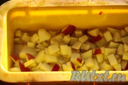 На дно формы для хлеба или кекса вылить карамель. Яблоко нарезать небольшими кубиками и выложить на карамель.