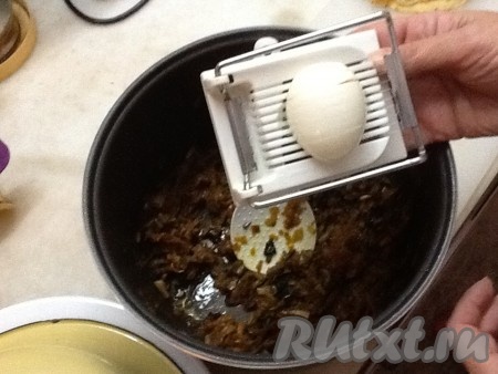 Отварить 2 яйца и добавить их в начинку через яйцерезку, перемешать.