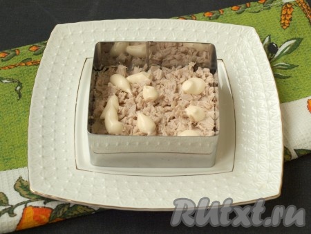 По центру плоской тарелки разместить формочку и выложить измельчённое филе индейки или курицы. Салат также можно приготовить в глубоком салатнике. Филе смазать майонезом. 