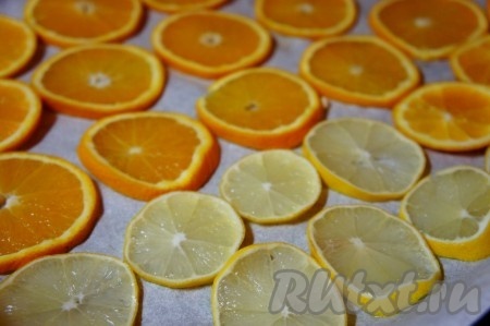 Противень застелить пергаментной бумагой. Выложить нарезанные апельсины и лимоны. 