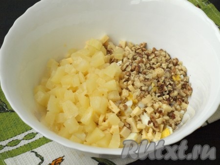 Измельчить консервированные ананасы, порубить ножом грецкие орехи и добавить в салат.
