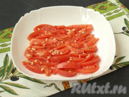 Помидоры нарезать соломкой и выложить на дно тарелки. Посуду лучше взять с небольшим углублением. Измельчить зубчик чеснока и посыпать сверху на помидоры.