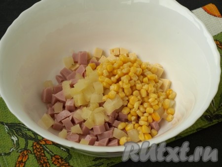 Слив с ананасов сок, нарезать их кубиками и добавить к ветчине и сыру. Слить сок с кукурузы и добавить её в салат к остальным ингредиентам.
